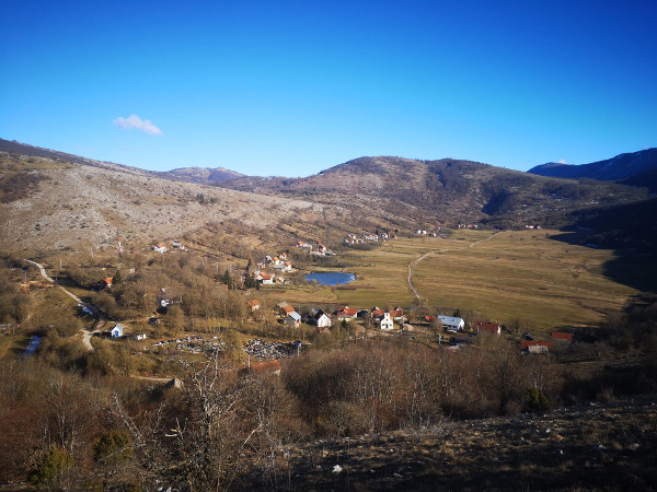 Pogled na dolinu i selo Veliki Čanak sa zapada; ističe se velika lokva koja je nekoć služila za napajanje stoke i pranje rublja (Foto: Mate Furlan; Izvor: Facebook zajednica Svi koji znaju za ličko selo Čanak, 16. veljače 2022.)