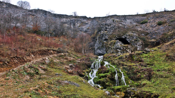 Ulaz u Siničić špilju, iz kojega nakon kišnih razdoblja istječe potok koji je nekoć pokretao mlinice (Izvor: Lika Online (lika-online.hr); Foto: Dražen Prša, 2015.)