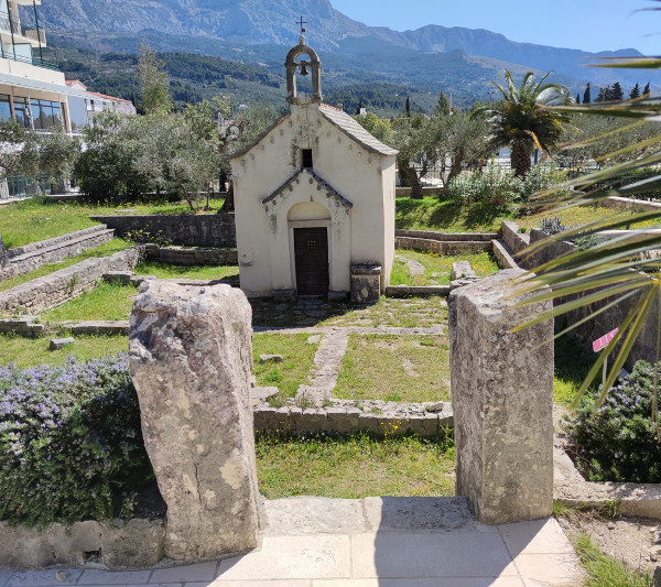 Ulaz u ograđeni prostor oko crkve Sveti Juraj u Tučepima, izgrađen od monolita koji su izvorno bili polegnuti nadgrobni spomenici (”stećci”) na mjesnome groblju (Izvor: Facebook stranica Turistička zajednica općine Tučepi - Tourist Board, post od 23. travnja 2022.)